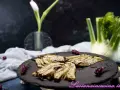 Finocchi croccanti e dorati, cotti nella friggitrice ad aria, serviti su una pietra scura con erbe aromatiche.