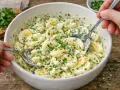 Cremiger Eiersalat mit Schnittlauch, perfekt für ein schnelles eiersalat rezept. Zwei Löffel greifen in die Schüssel.