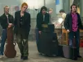 Les membres des Sex Pistols se tiennent prêts pour un concert, guitare et amplis à portée de main.