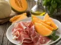 Piatto con fette di prosciutto e spicchi di melone, un classico antipasto italiano.