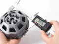 A caliper measures a 3D printed part, showcasing the precision of 3D printing.