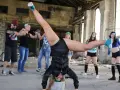 Grupa młodych ludzi tańczy w opuszczonym budynku. Jedna z dziewczyn wykonuje efektowną figurę, stojąc na rękach. To właśnie dancehall!