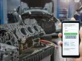 Mechanic uses phone to diagnose P2097 code, showing "Post Catalyst Fuel Trim System Too Rich Bank 1" on screen, with car engine parts in background.