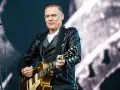 Bryan Adams w skórzanej kurtce gra na gitarze, przypominając piosenkę z Robin Hooda.