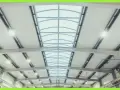 Interno di un capannone con luminose coperture industriali e lucernari curvi che illuminano lo spazio.