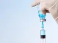 Rękawiczka pobiera płyn do strzykawki. To może być mmr szczepionka, chroniąca przed chorobami.