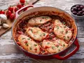 Succulento pollo alla pizzaiola in padella, con pomodoro, olive e capperi, guarnito con prezzemolo fresco.