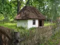 Drewniana chata z krytym strzechą dachem i płotem z gałęzi. Wspaniałe radom atrakcje, które przenoszą w przeszłość.