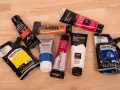 Des tubes de peinture acrylique de diverses couleurs et marques, prêts à se mettre à la peinture.