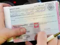 Ręka trzyma mandat karny na kwotę 300 zł, obok dowód osobisty. To kara za wykroczenie, być może związane z parkowaniem.