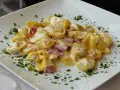 Tortellini panna e prosciutto, un piatto cremoso e saporito, guarnito con prezzemolo fresco su un piatto bianco.