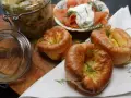 Drei goldbraune Yorkshire Pudding mit Dill garniert, daneben Lachs mit Frischkäse und ein Glas Sauerkraut.