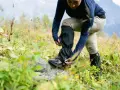 Une personne ajuste ses guetres de randonnée dans un paysage naturel.