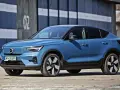 Niebieskie Volvo C40, elektryczny SUV coupe, parkuje przed budynkiem z numerem "02".