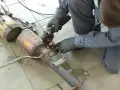 Meccanico con smerigliatrice effettua la rimozione fap da un pezzo di scarico auto, scintille volano.
