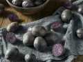 Ein Haufen blauer Schwede Kartoffeln, einige ganz, andere halbiert, liegen auf einem grauen Tuch.