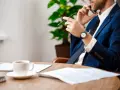 Biznesmen rozmawia przez telefon, trzymając długopis. Na stole kawa i dokumenty. Pytanie: na ile rat sąd może rozłożyć zadłużenie?