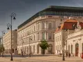 Elegancka kamienica z nowoczesnym dachem, być może najdroższy hotel w Polsce, przy słonecznej ulicy z zabytkowymi latarniami.