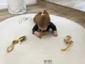 Niemowlę na brzuchu na macie z motywem roślinnym bawi się drewnianymi gryzakami.