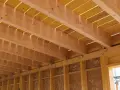 Vue détaillée de comment réaliser le solivage d'un plancher d'étage : poutres en bois, panneaux jaunes et supports métalliques.