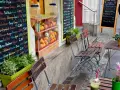 Frischer Smoothie in Berlin. Bunte Tafel mit Frucht- und Gemüsesorten, daneben leere Stühle und ein Tisch.