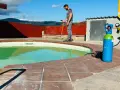 Técnico trabajando en el borde de una piscina, con equipo para impermeabilizar piscina.
