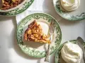 En härlig bit tosca kaka med mandlar, serverad på en grönmönstrad tallrik med en gaffel och en klick vispad grädde.