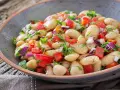 Un'insalata di fagioli sfiziosa, ricca di pomodori freschi, cipolla rossa e erbe aromatiche, servita in una ciotola rustica.