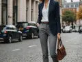 Elegancka stylizacja: granatowa marynarka, biała koszula i brązowa torebka to idealne dopełnienie tego, co pasuje do szarych spodni damskich.
