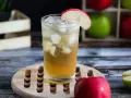 Orzeźwiający drink z sokiem jabłkowym, lodem i plasterkiem jabłka, gotowy do degustacji.