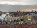 Vista dal **fondaco dei tedeschi Venezia terrazza** al tramonto, con il Canal Grande e il Ponte di Rialto illuminati.