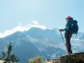 Kobieta z plecakiem i kijkami trekkingowymi podziwia majestatyczne góry podczas trekkingu pod Mount Everest.