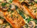 Två saftiga laxfiléer serveras i en krämig sås med spenat och champinjoner. En härlig fiskgryta med potatis som tillbehör.