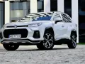 Biały Suzuki Across z czarnymi detalami stoi przed nowoczesnym budynkiem.