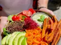 Ein bunter Buddha Bowl mit Avocado, Quinoa, Süßkartoffel-Pommes und Karottenrosen. Ein froindlichst Berlin-Genuss!