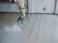 Pracownik wyrównuje świeżą wylewkę betonową. Czas, ile schnie wylewka betonowa, zależy od wielu czynników.