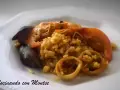 Arroz meloso con langostinos, mejillones y calamares en un plato blanco.