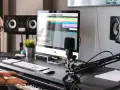 Producent muzyczny gra na pianinie w studiu, otoczony sprzętem, w tym monitorami studyjnymi EVE Audio SC307.