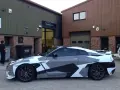A Nissan GT-R with a striking geometric camouflage vinyl wrap for cars, parked outside a building with "WRAPTITION" signage.