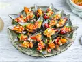 Mejillones a la vinagreta, frescos y coloridos, servidos en su concha con una picada de pimientos y cebolla.