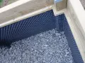 En nybyggd platonmatta odlingslåda med dränerande grus och skyddande plastmatta.