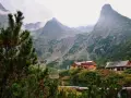 Malownicze tatry słowackie z górami w chmurach, jeziorem i schroniskami.