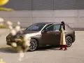Elegancka kobieta w beżowej sukience i czerwonych kozakach zbliża się do brązowego Maserati SUV.