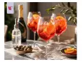 Idealny Campari Spritz przepis na letnie popołudnie. Trzy kieliszki pełne orzeźwiającego drinka z pomarańczą i lodem.