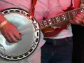 Ein Mann spielt ein Banjo, ein Saiteninstrument mit einem runden Korpus und einem langen Hals.