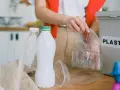 Segregacja odpadów to pierwszy krok, jak ograniczyć plastik. Ręka wrzuca plastikowe opakowania do pojemnika z napisem "PLASTIC".