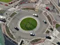 Rotonda con piste ciclabili e segnaletica orizzontale che rispetta l'art. 36 CDS. Auto e camion circolano in un contesto urbano moderno.