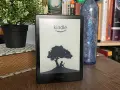 Czytnik Kindle z grafiką drzewa i siedzącą pod nim postacią. Idealny do przechowywania wielu **plików epub**.