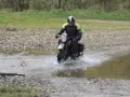 Motocyklista w kasku pokonuje wodną przeszkodę na kamienistej trasie w okolicach Jasła.