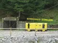 Wejście do sztolni Kowary z żółtym wagonikiem górniczym i napisem "KOWARSKIE KOPALNIE".